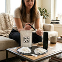 Woman sitting on a couch using a NAVA product in a living room setting.