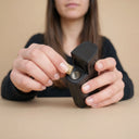 Person holding a black vape device with a beige background